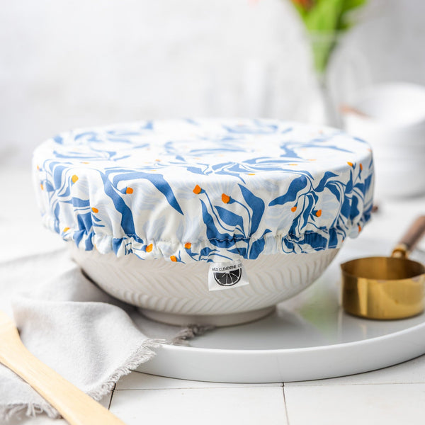 White bowl with a blue floral patterned cover on a white surface with a blurred background