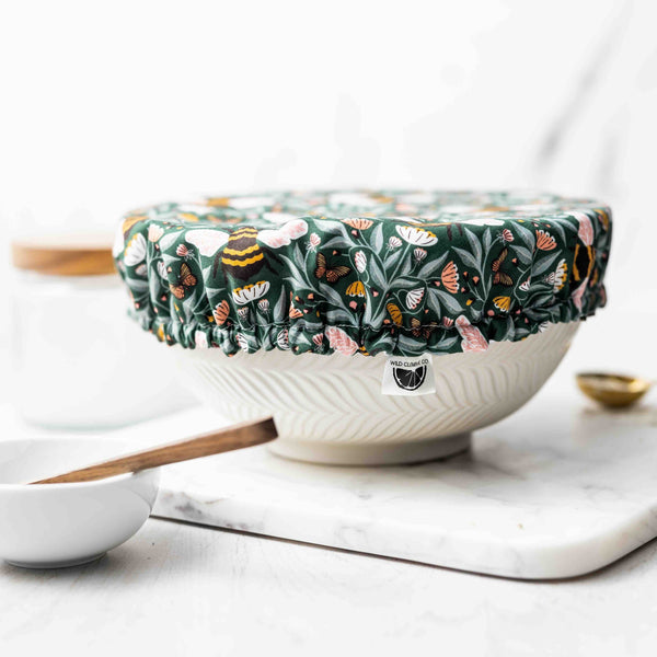 Floral-patterned food cover on a bowl with utensils on a marble surface