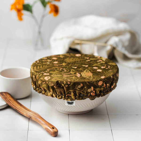 Decorative green lid on a white bowl with a white background and flowers.