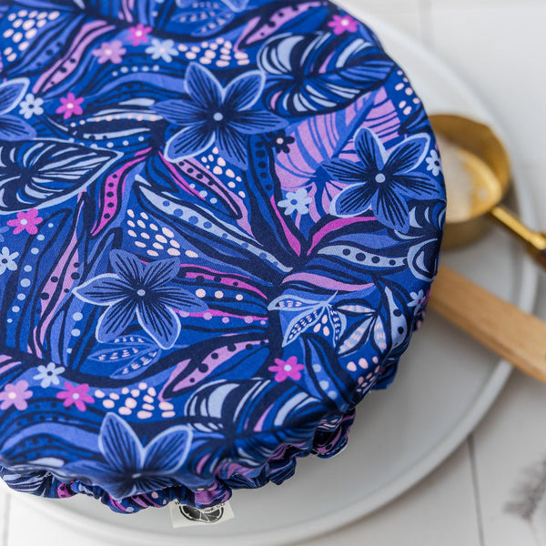 Blue floral-patterned cake cover on a white cake with a gold spatula