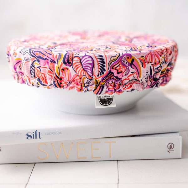 bowl with colorful dish cover on a stack of cookbooks