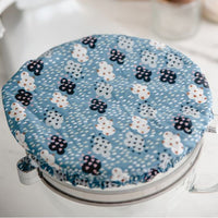 Eco-friendly reusable dish cover, blue with navy, aqua, and white clouds covered in stars and hearts, with raindrops