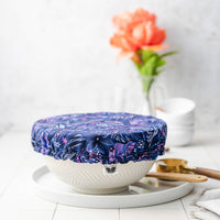 Blue floral-patterned dish cover on a white container with a white background and decorative elements.