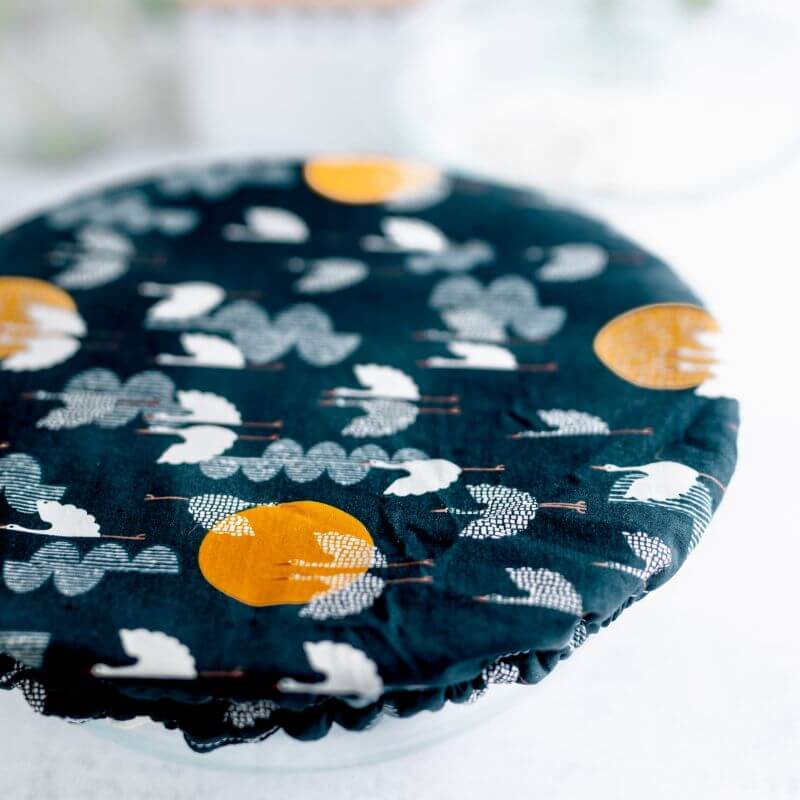 Deep cobalt blue reusable bowl cover with cranes flying amongst clouds and moons print