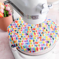 White reusable bowl cover with rows of watercolor rainbow dashes on a Kitchenaid Mixer Bowl