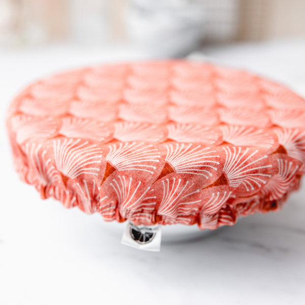 Coral scallop printed reusable dish cover on a white bowl