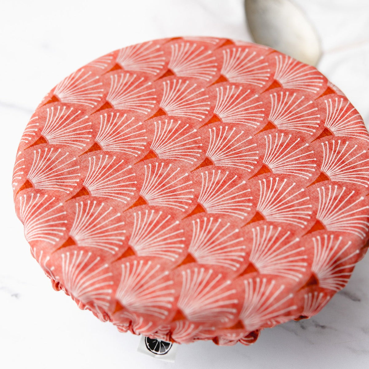 Coral scallop printed reusable dish cover on a white bowl