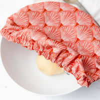 Coral scallop printed reusable dish cover on a white bowl