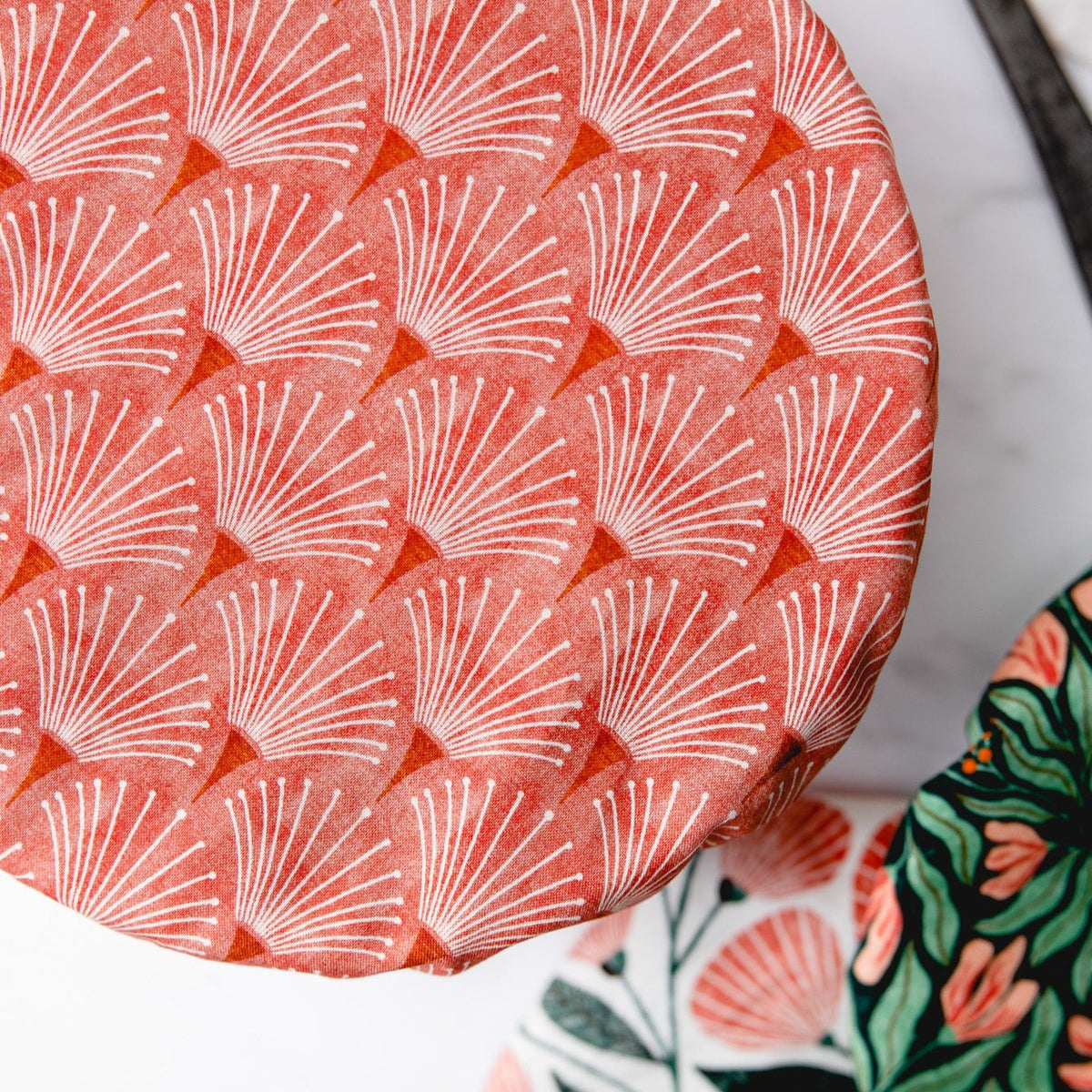 Coral scallop printed reusable dish cover on a white bowl