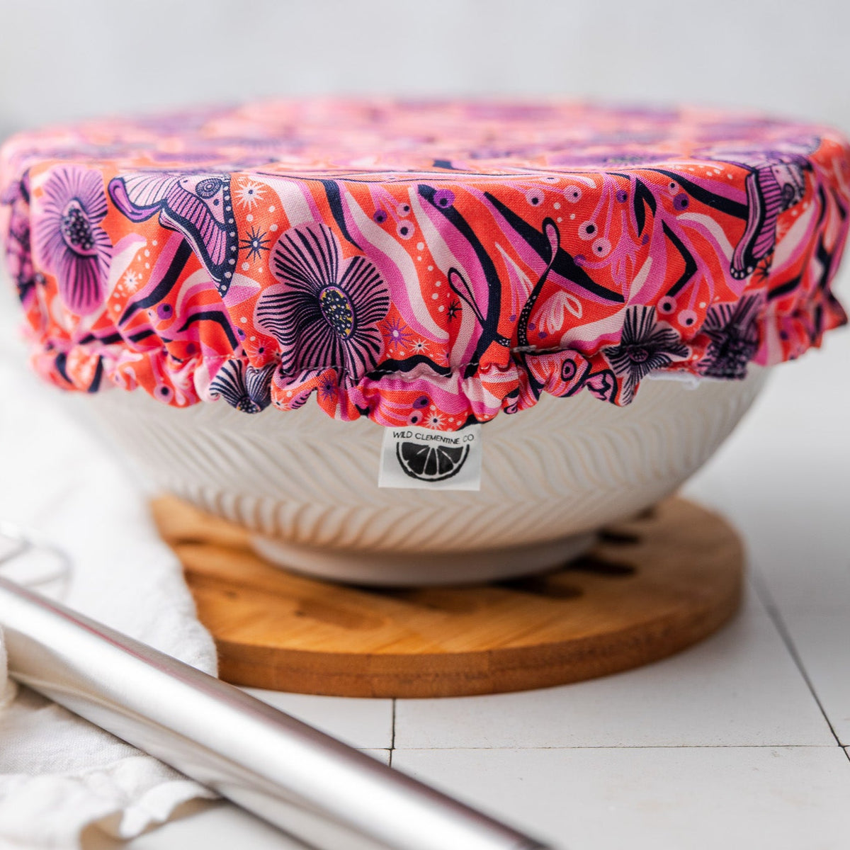 White bowl with a colorful moth-patterned lid on a white surface