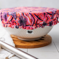 White bowl with a colorful moth-patterned lid on a white surface
