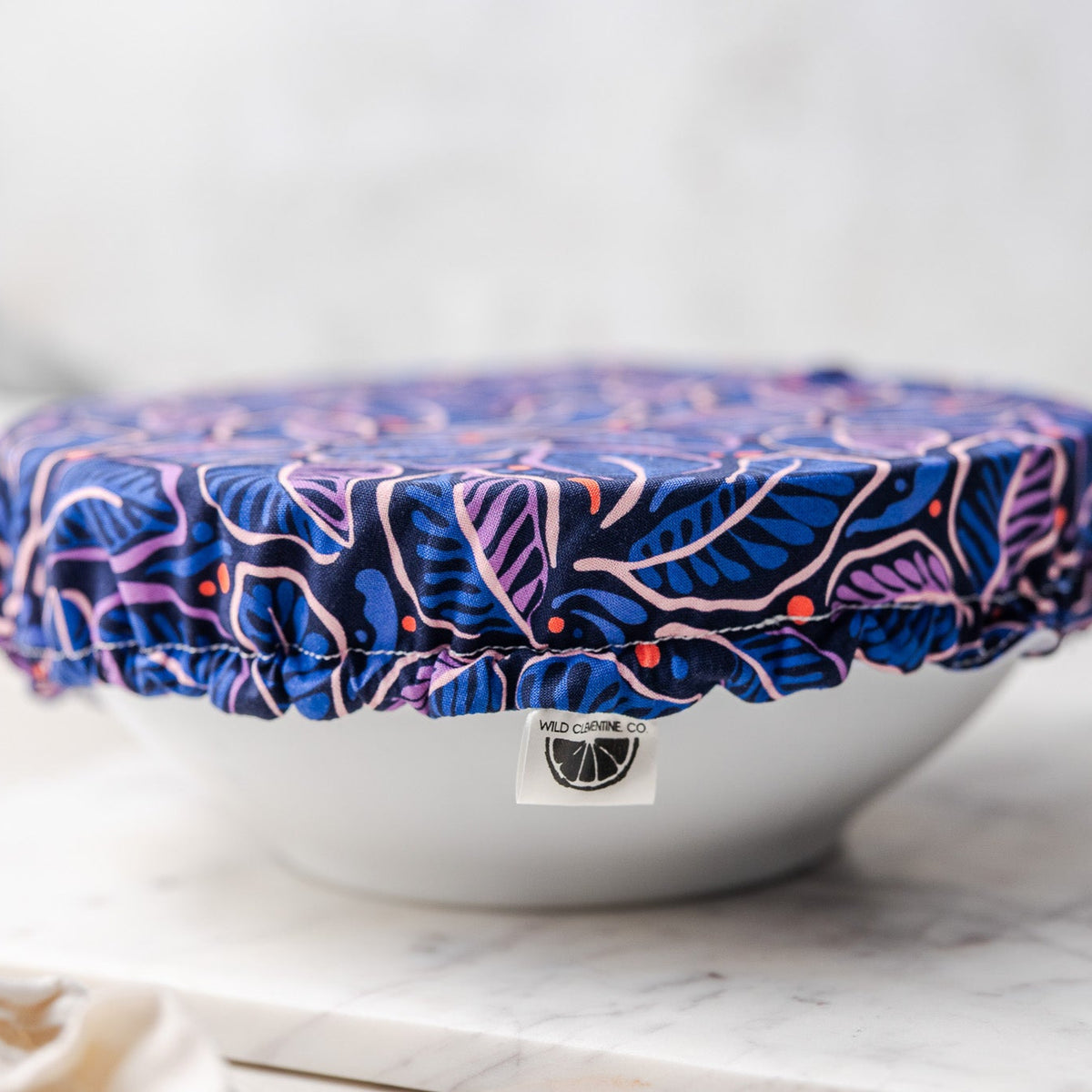 White bowl with a blue floral cover on a marble surface
